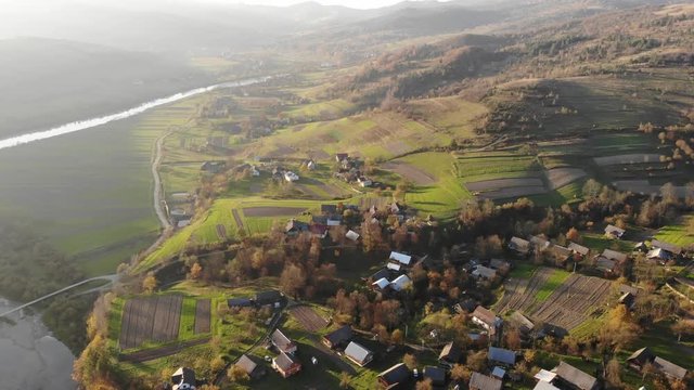 Aerial view of old village in Carpathians with traditional architecture, fields, roads and river. Autumn time, travel in Western Ukraine. Fly forward