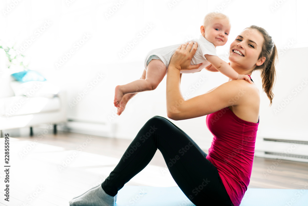 Poster a portrait of beautiful young mother in sports wear with her charming little baby in training sessio