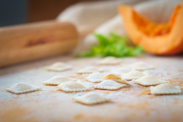 traditional raw ravioli with pumpkin on a wooden table with flour, handmade, cooking process