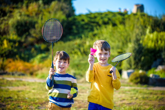 Active Preschool Girl And Boy Playing Badminton In Outdoor Court In Summer. Kids Play Tennis. School Sports For Children. Racquet And Shuttlecock Sport For Child Athlete.