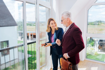 Some hesitations. Bearded businessman wearing elegant jacket hesitating about buying new house standing near estate agent © zinkevych