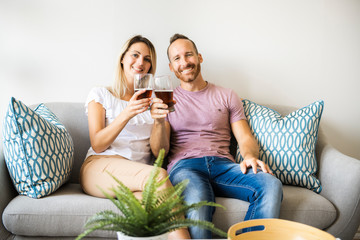 Relaxed young couple watching tv and drinking beer at home