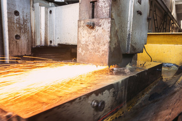 Grinding parts on the machine with water. Metal processing with sparks on a flat grinding machine.