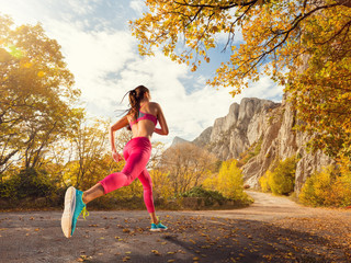 Young woman running on a mountain road in the beautiful nature. Girl runner in sneakers jogging...