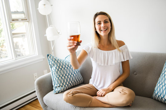 Woman Drinking Beer Sitting On A Couch In The Living Room At Home