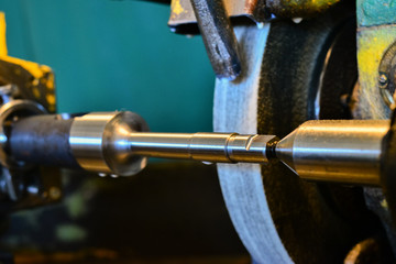 The iron cylindrical part is mounted on a grinding machine, close-up.