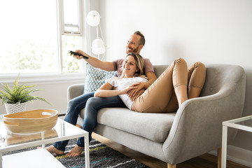 Couple watching tv at home sitting in a comfortable couch in the livingroom at home