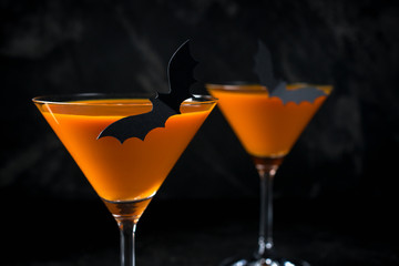 Orange pumpkin  martini Halloween drink for party over black background with copy space