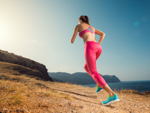 Woman running. Young girl runner jogging on a mountain trail in the beautiful landscape. Healthy sport lifestyle. Fitness and workout on outdoors.