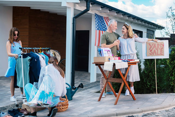 Visiting sale. Two young dark-haired women watching different clothes and shoes coming to their...