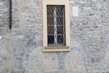 Fototapeta na wymiar finestra in legno con sbarre ferro battuto e mura antiche