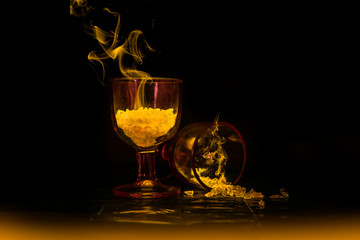 Amber glowing drinks in small wine glasses with smoke