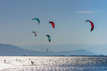 Colored kite surfers on riding waves on mediterranean sea