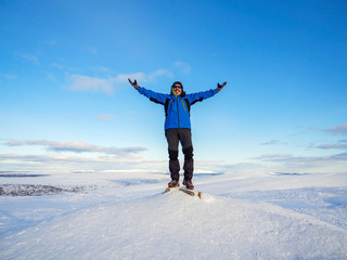 A man at the top of a snowy mountain with his hands up