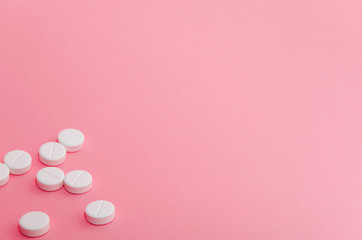 Close-up of pills in the left-down corner of the pink background