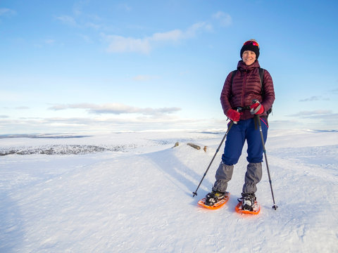 Pretty, young woman snowshoeing and enjoying splendid winter weather with abundance of snow