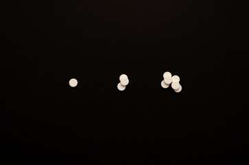 Three handfuls of pills on black background