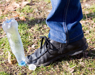 human trampled with the feet of plastic mineral water bottles and bottle caps on the grass in the park, the concept of environmental protection, fouling the environment