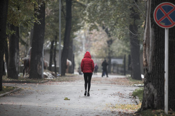 girl in a red jacket walks in the autumn park