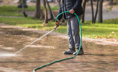 worker watering the sidewalk