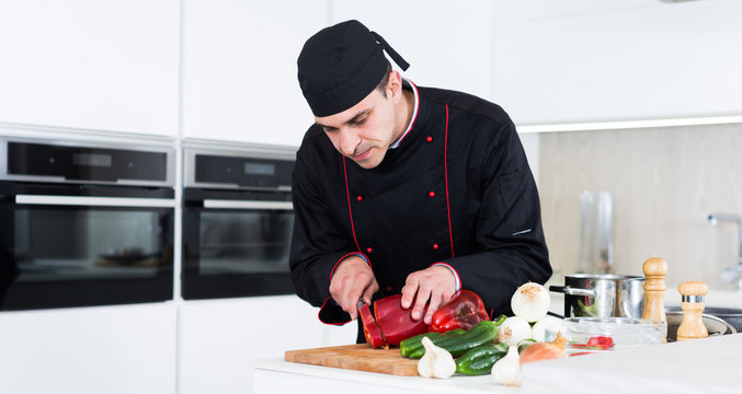 Male cook is making salad on his work place in the kitchen