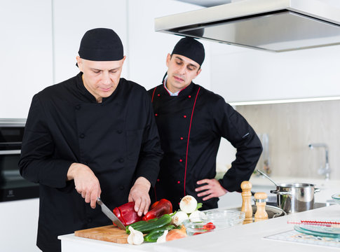 Professional men chefs  in black uniform working together
