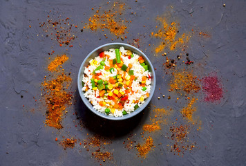 Rice with vegetables and spices on dark blue concrete background. Vegetarian food, products for proper nutrition, close up, copy space,flat lay