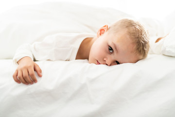 cute four years boy in white bedding