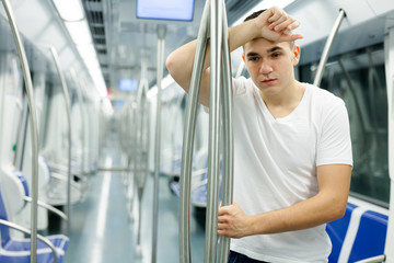 Fototapeta na wymiar Tired man standing in underground carriage