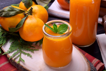 Orange smoothie topped with mint in glass jars surrounded by fruits © kcuxen