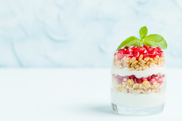 Pomegranate parfait - sweet organic layered dessert with granola flakes, yogurt and ripe fruit seeds.
