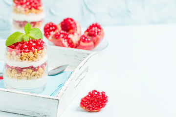 Pomegranate parfait - sweet organic layered dessert with granola flakes, yogurt and ripe fruit seeds.