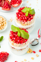 Pomegranate parfait - sweet organic layered dessert with granola flakes, yogurt and red ripe fruit seeds.