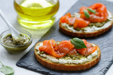 Bread toast with salted salmon, pesto sauce and cream cheese (ricotta). Gourmet snack. selective focus