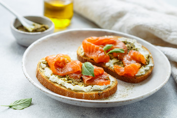 Bread toast with salted salmon, pesto sauce and cream cheese (ricotta). Gourmet snack. selective focus