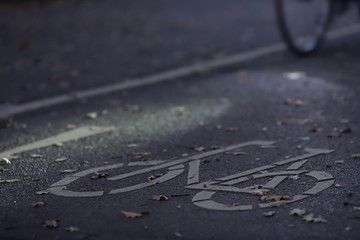 oblique view on cycle path at morning dawn with an illuminated bike and defined light spot- urban commuting concept - blurred background - copy space for text