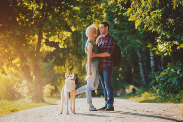 Dog with owners spend a day at the park. Young couple and husky running, playing and having fun.