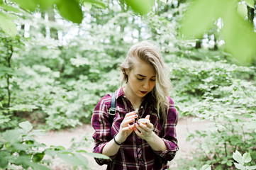 Portrait of an attractive blond girl posing with a compass in a forest.