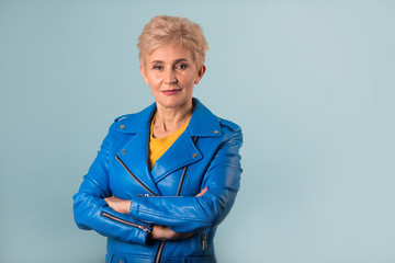stylish woman at the age with a short hairstyle in a blue jacket on a blue background