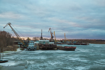Pier with cargo ships on the frozen river.