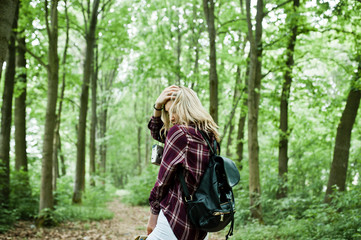Fototapeta na wymiar Portrait of a young beautiful blond woman in tartan shirt holding a map in the forest.