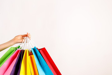 Cropped shot of female hand holding bunch of different colorful blank shopping bags over isolated...