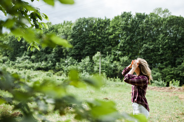 Close-up portrait of a smiling blond girl in tartan shirt in the countryside.