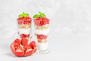 Pomegranate parfait - sweet organic layered dessert with granola flakes, yogurt and ripe fruit seeds.