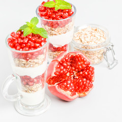 Pomegranate parfait - sweet organic layered dessert with granola flakes, yogurt and red ripe fruit seeds.