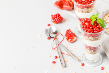 Pomegranate parfait - sweet organic layered dessert with granola flakes, yogurt and ripe fruit seeds.