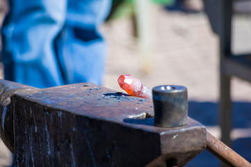 blacksmith performs the forging of hot glowing metal on the anvil
