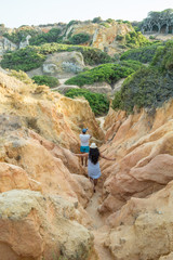 People hiking between the hills of Praia dos Pinheiros in Lagos, Portugal