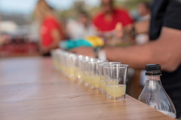 Pouring alcoholic beverage into shot glasses in a row.