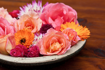 Bowl filled with autum flowers in warm colors of orange and pink